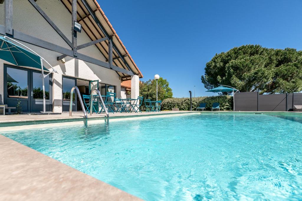 a swimming pool with blue water in front of a building at Hôtel Le Roxane in Bergerac