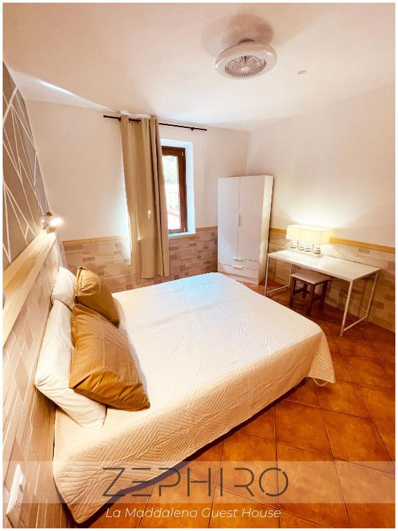 a bedroom with a large bed and a table at Zephiro Guest House in La Maddalena