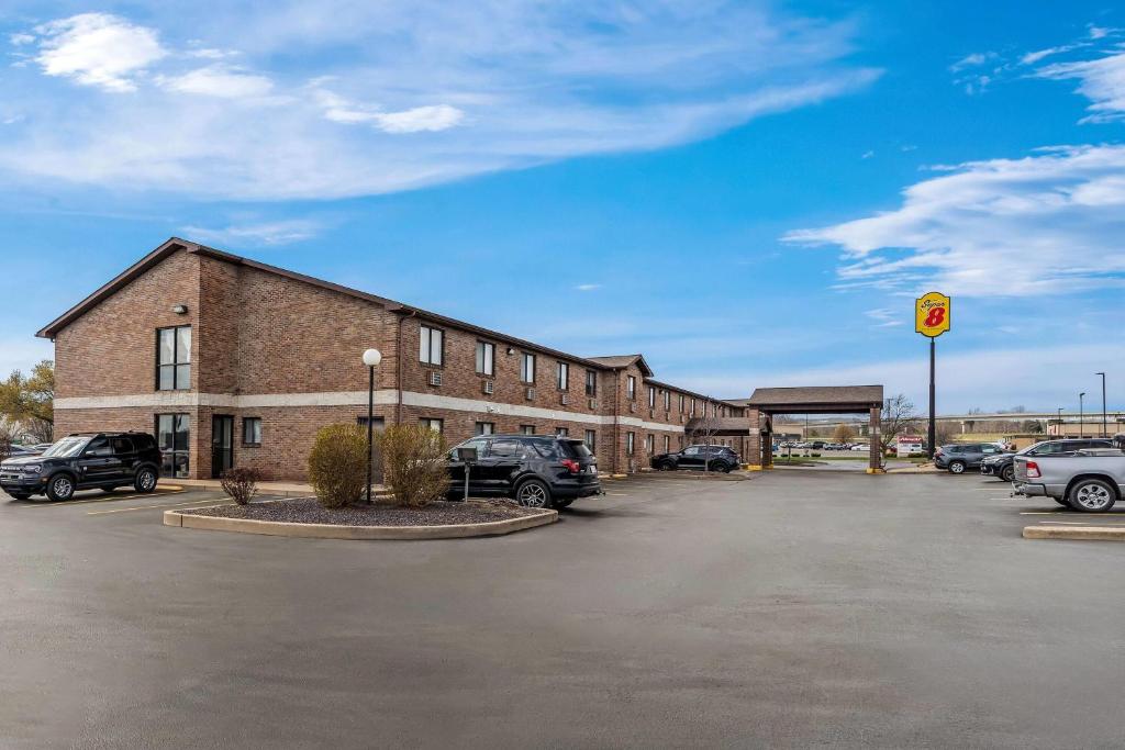 a brick building with cars parked in a parking lot at Super 8 by Wyndham Farmington in Farmington