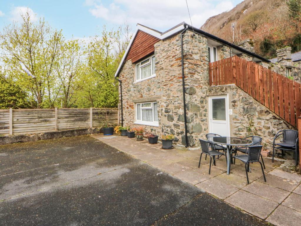 a stone house with a table and chairs in front of it at Ground Floor Apartment in Porthmadog