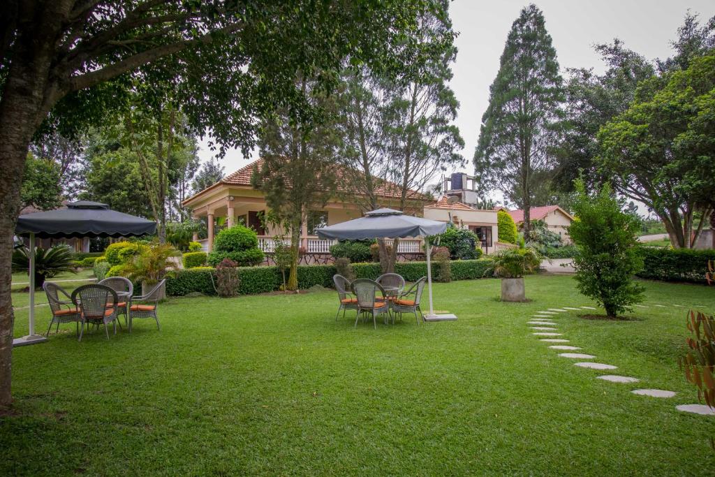 - une cour avec des chaises, des tables et un parasol dans l'établissement Tuzza Hotel, à Bushenyi