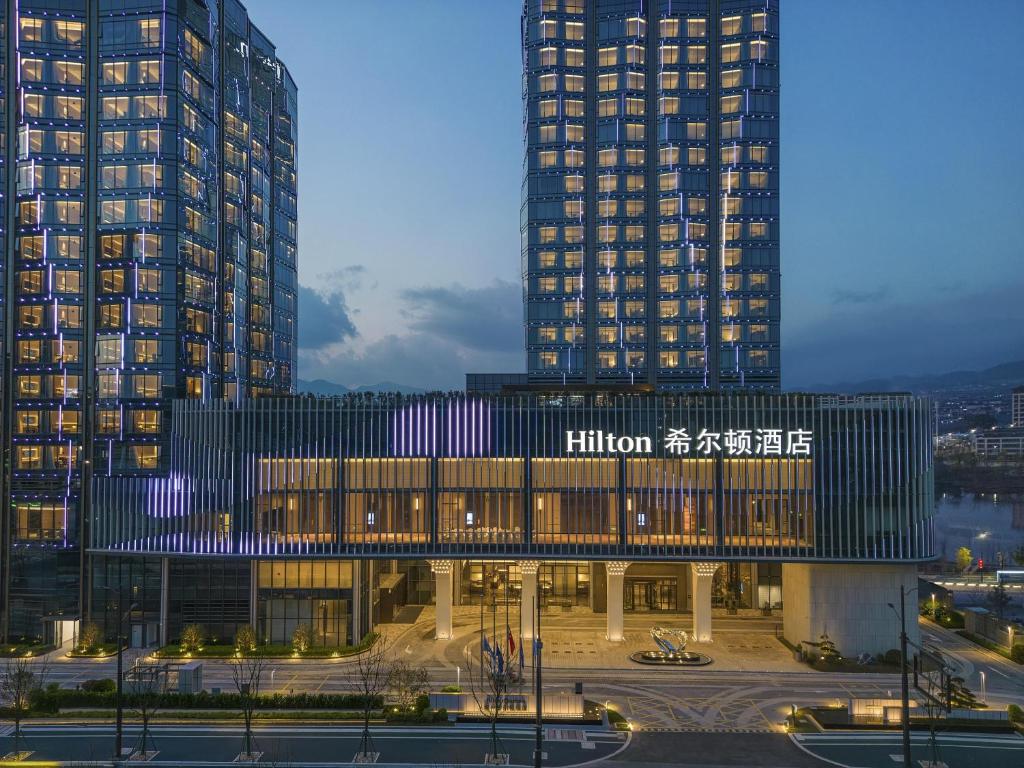 a building with two tall buildings in a city at Hilton Quzhou in Quzhou