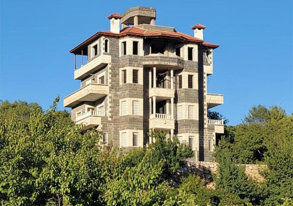 an old building on top of a hill with trees at Zaytouna Farm in Ajloun