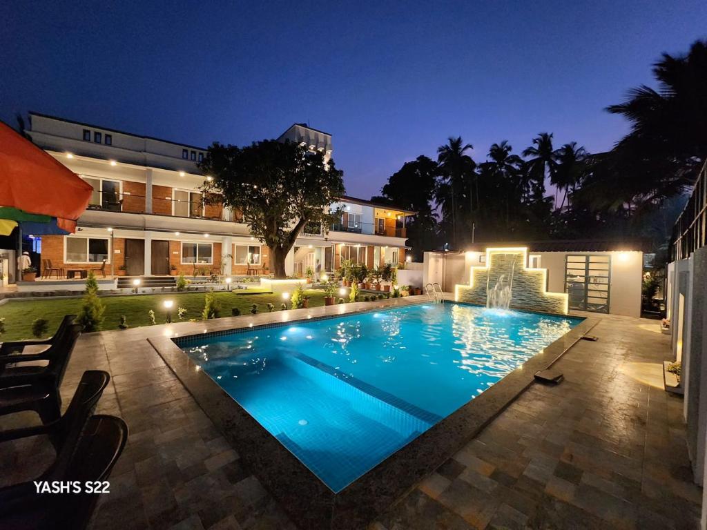 a swimming pool in front of a building at night at Basil Leaf Resort in Varsoli