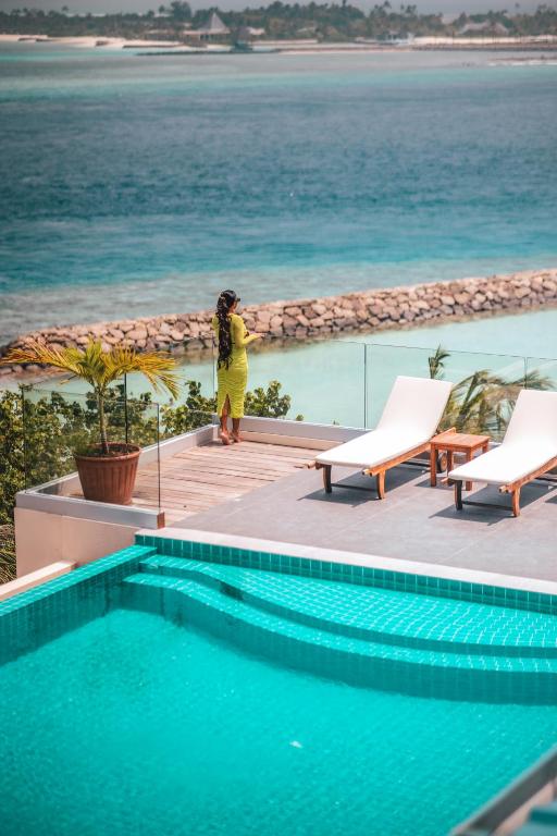 a person in a yellow suit standing next to a swimming pool at Season Paradise in Thulusdhoo