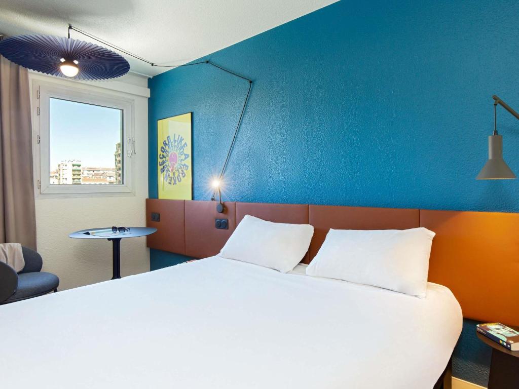 a bedroom with a large bed and a blue wall at ibis Marseille Timone in Marseille