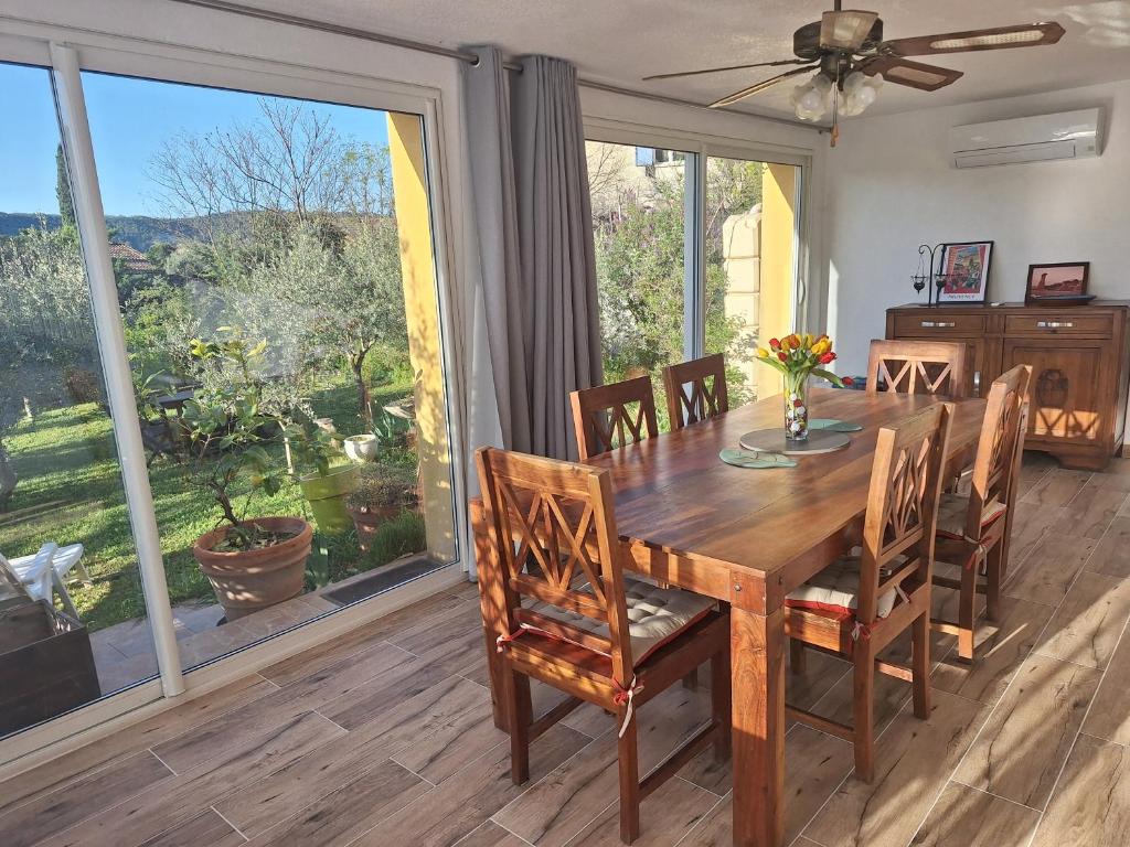 a dining room with a wooden table and a large window at Maison Rustrel clim 3 chambres entre ocres et lavandes in Rustrel