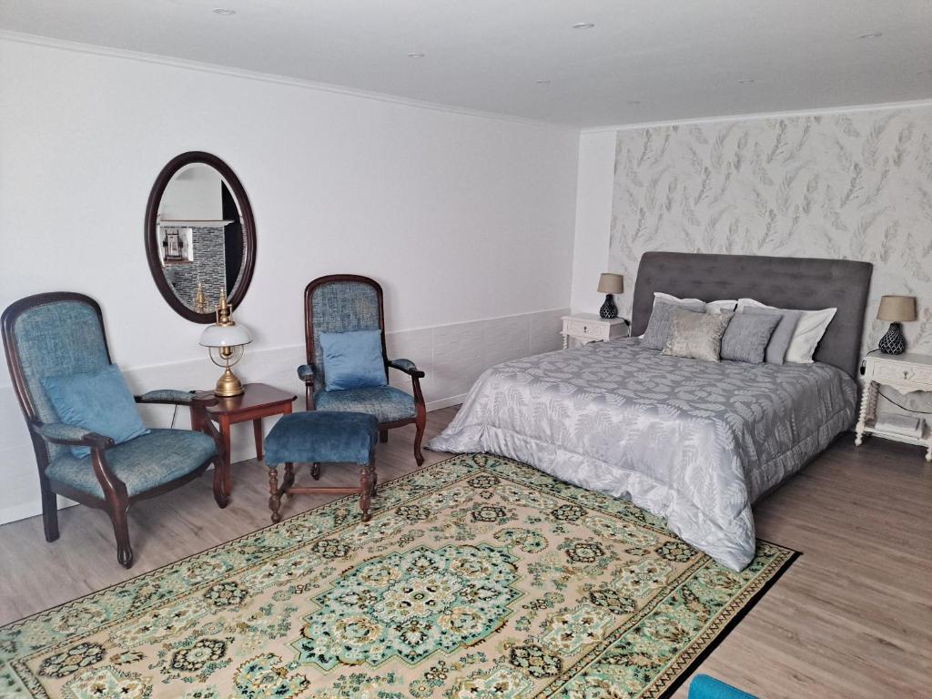 a bedroom with a bed and two chairs and a mirror at Casa Do Cais in Setúbal