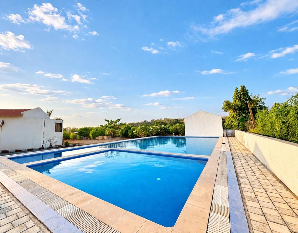 an image of a swimming pool with blue water at Vanray Farm And Resort in Talala