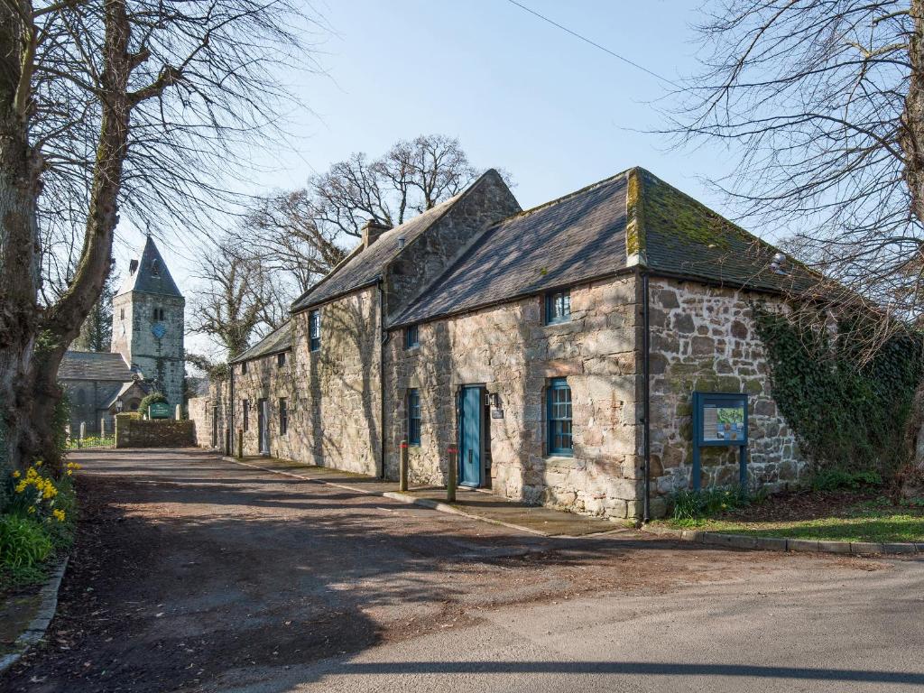 an old stone building with a church in the background at The Old Coach House in Alnwick