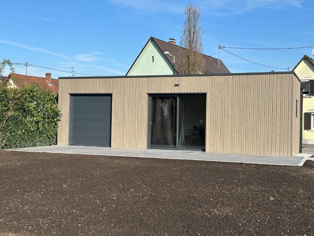 a building with a garage with a driveway at Au loft, micro maison vue sur prairie in Rohrwiller