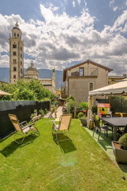 a yard with chairs and a table and a clock tower at Casa Vacanza Nonna Pia I & III in "Piazza Basilica" in Tirano