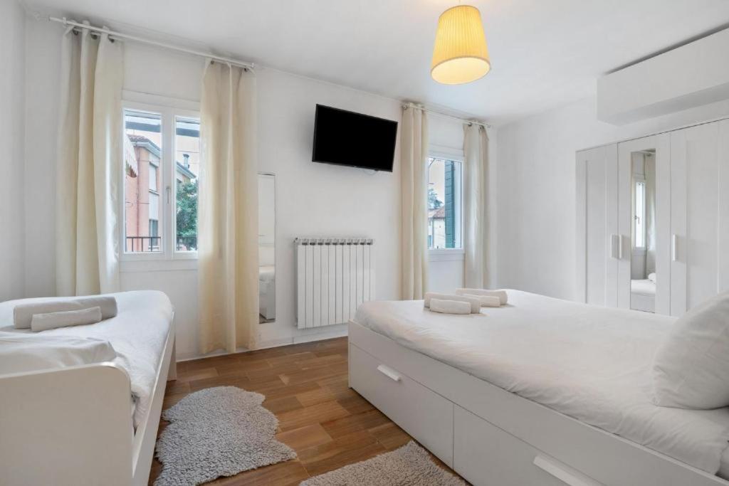 a white bedroom with a large bed and a tv at Venezia, 15 minutes from Venice, Parking,Shuttle airport, Train station Miranese in Mestre