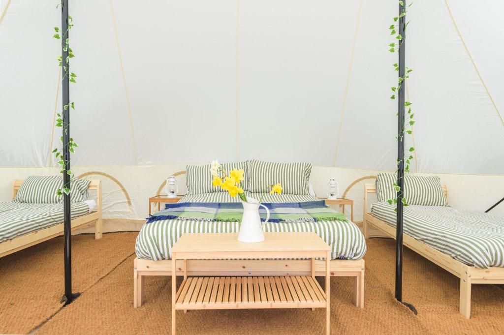 a room with two beds and a vase with flowers on a table at Boscoppa Farm-Emperor Tent 1 in St Austell