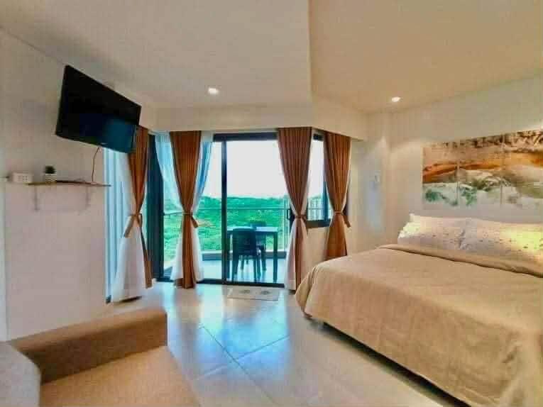 a bedroom with a large bed and a large window at Seaside Living Studio Unit in Maribago
