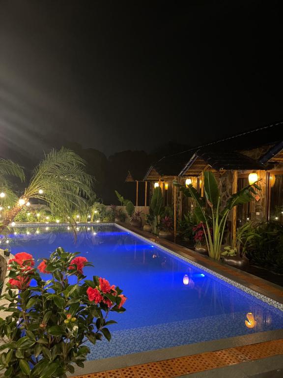a swimming pool at night with flowers and lights at Flora Garden Homestay in Xuân Sơn