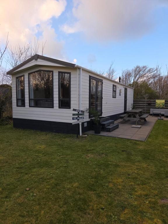 a small white house with a picnic table and benches at Chalet Casa Quak in Petten