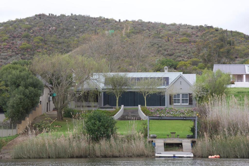 a house with a boat on the water at Misty Moon in Malgas