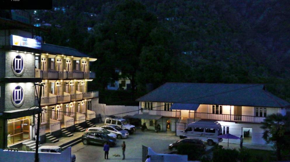 a building with cars parked in a parking lot at night at Young Monk Hostel Bhagsu,Mcleodganj in Dharamshala