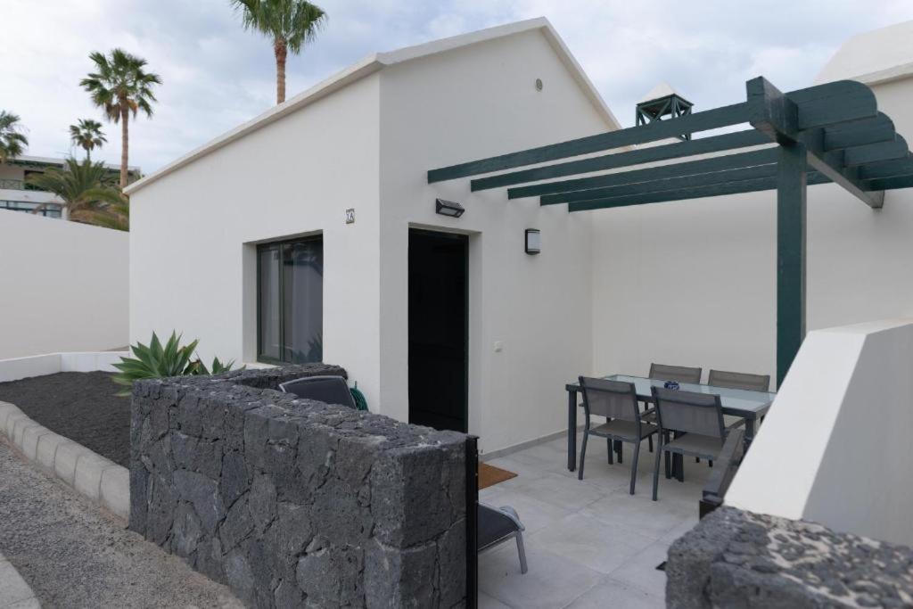 a white house with a patio with a table and chairs at CASA IBON 1A pool view Playa Roca in Costa Teguise