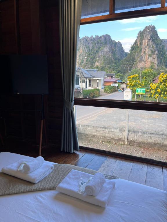 a bed with towels on it with a large window at ค้างคาวกินกล้วยโฮมสเตย์ in Ban Mung