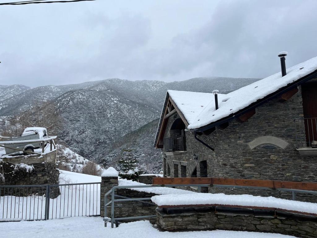 a building covered in snow with mountains in the background at Àtic el Paller de Llau in Caregné