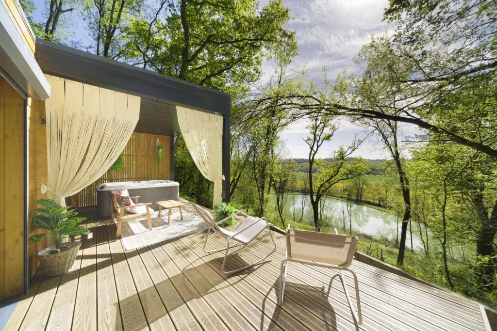 a deck with a view of a river and trees at Les cabanes du Lac in Sévignac-Thèze