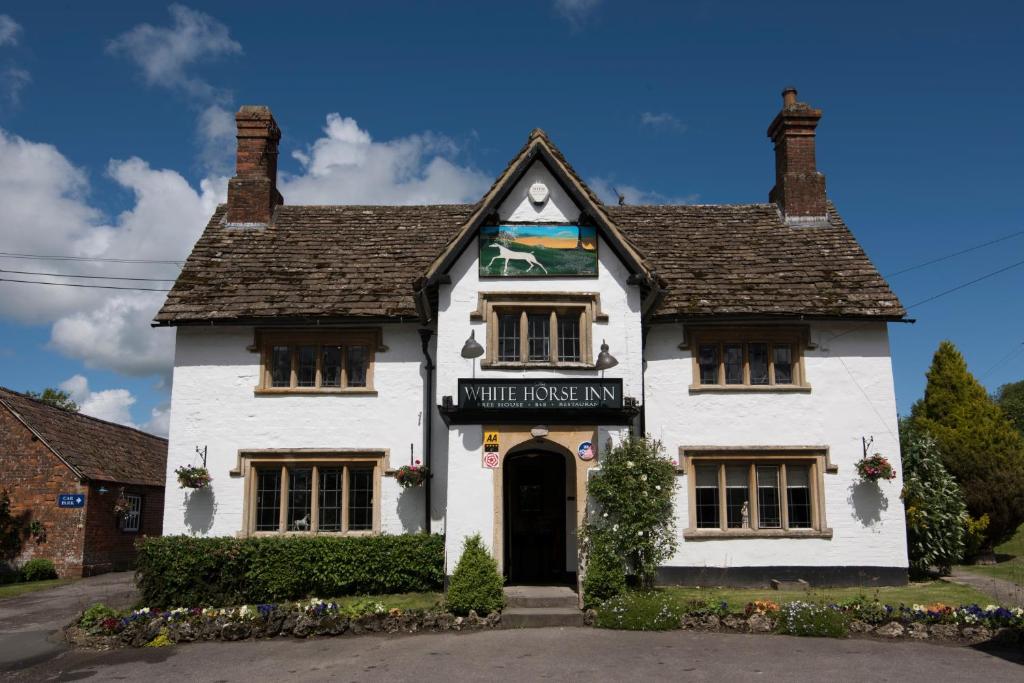 una casa bianca con un cartello che legge "La taverna dei lupi" di The White Horse Inn a Calne