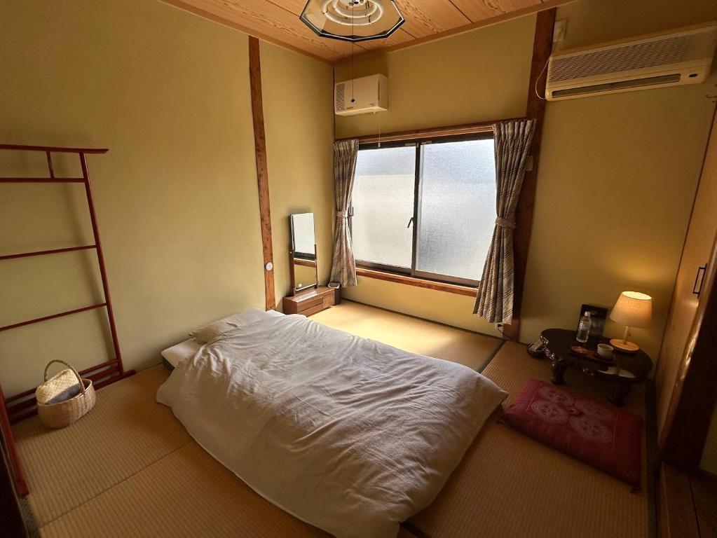 a bedroom with a white bed and a window at YADOease in Tsuiki