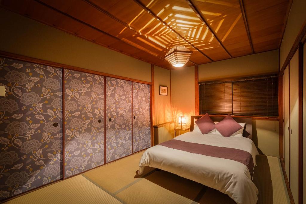 a bedroom with a bed with pink pillows at Chikyuutabikazoku USJ Ⅱ in Osaka