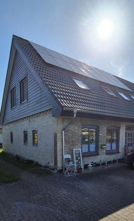 a house with a solar roof with a sign in front at Thirty Minutes in Ellingstedt