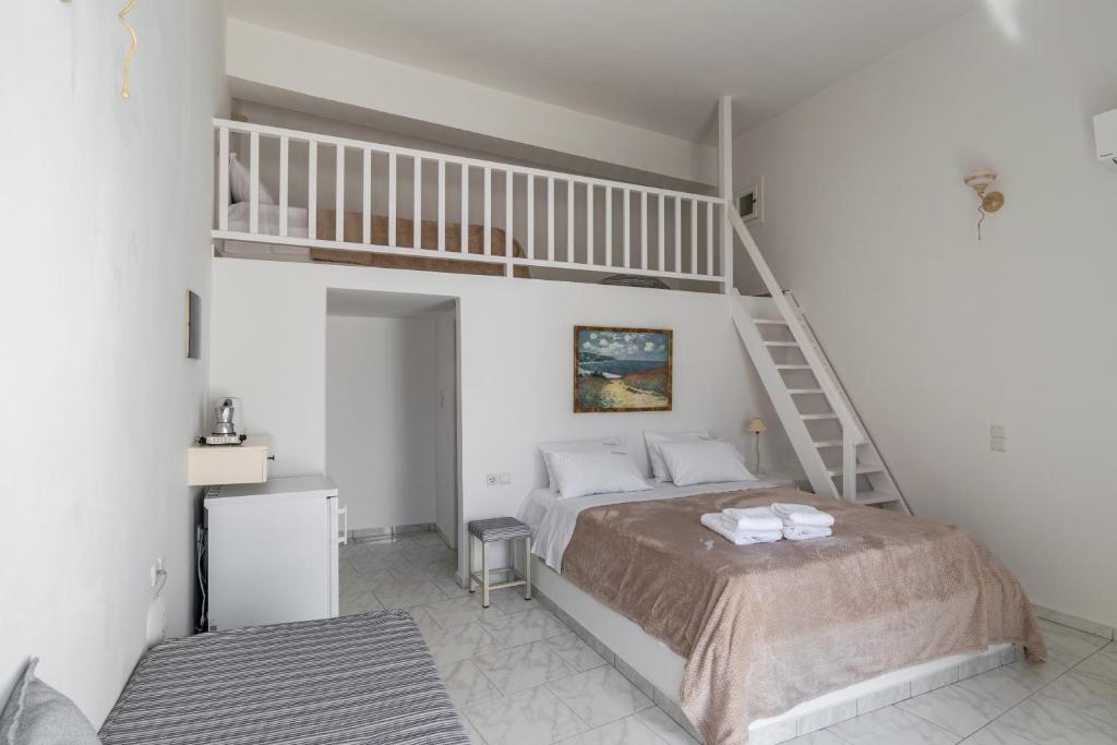 a white bedroom with a bed and a staircase at Livanios Studios in Adamantas
