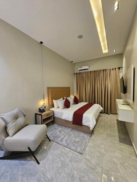 a bedroom with a bed and a chair and a television at Teestone Hotels and Apartment Ikeja in Lagos