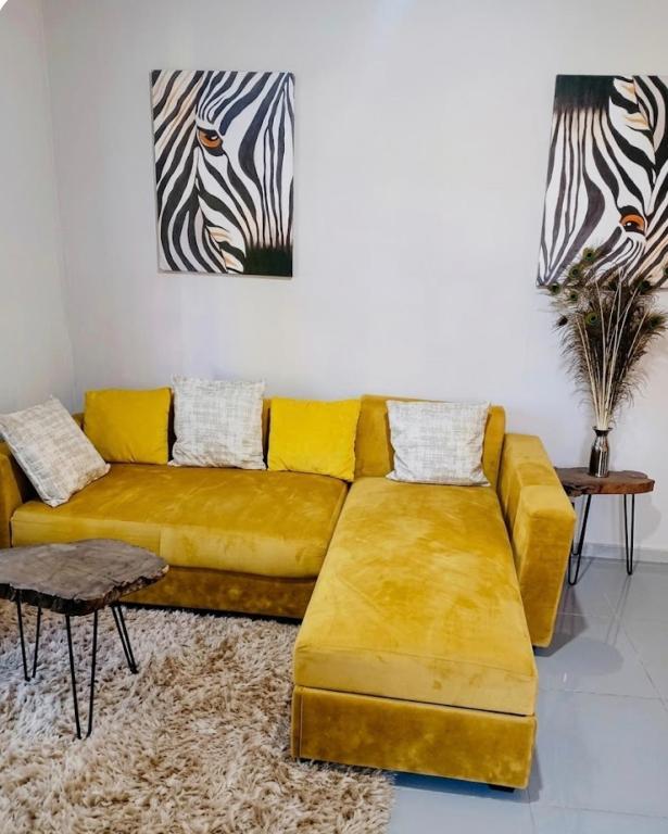 a living room with a yellow couch and a zebra painting at DeltaGateway selfcatering in Maun Airport