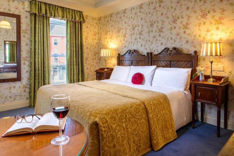 a bedroom with a bed and a table with a glass of wine at Arbutus Hotel in Killarney