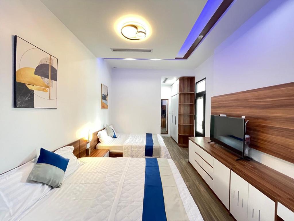 a bedroom with two beds and a flat screen tv at QV Manor - Homestay kề biển Bình Sơn in Phan Rang–Tháp Chàm