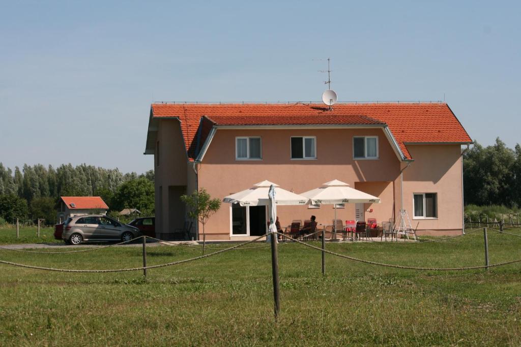 dom z parasolami przed nim w obiekcie Guesthouse Capistro w mieście Bilje