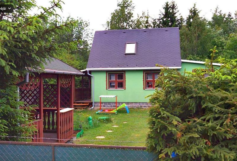 a green house with a yard with a playground at Zlatý Žabák in Suchý