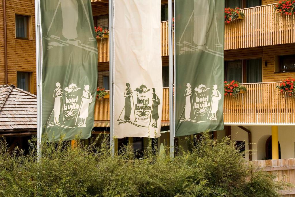 two green and white flags in front of a building at Hotel La Villa in La Villa