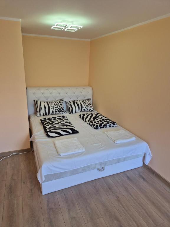 a bedroom with a white bed with black and white pillows at Apartman Jelena in Surčin