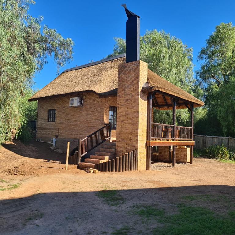 a small brick building with a roof with a porch at DuckPond Lodge Cottage in Oudtshoorn