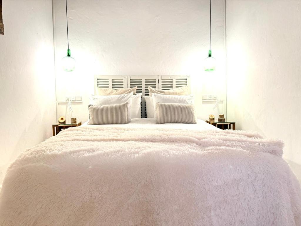 a white bedroom with a large white bed with pillows at Can PONÇ PARRA in Santanyi