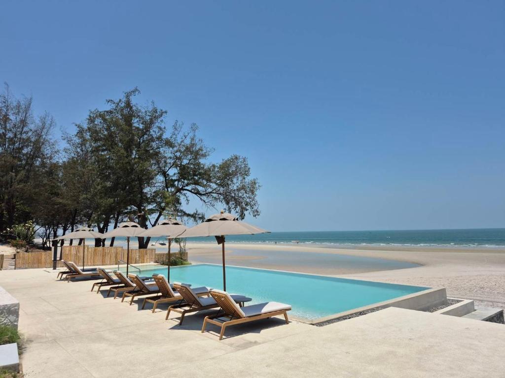 a row of chairs and umbrellas next to the beach at Riva Hua Hin in Ban Khao Takiap