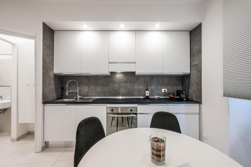 a kitchen with white cabinets and a table with chairs at La Scaletta 10 min from train station for Cinque Terre! in La Spezia