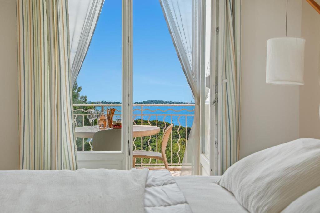 a bedroom with a bed and a balcony with a table at Duplex d'exception face à la mer in Hyères