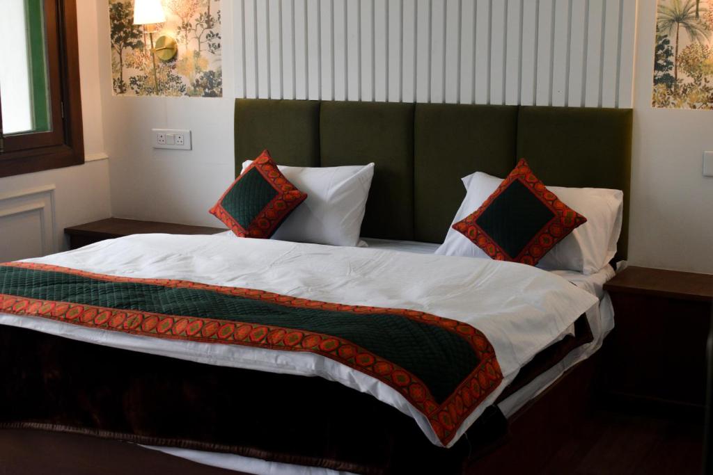 a bed with a green headboard and four pillows at The Himalayan Roots in Kulu