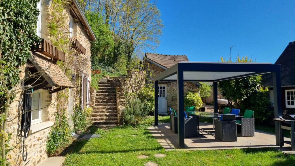 a pavilion with chairs and a table in a yard at Les Maisons de Mélody in Houlbec-Cocherel