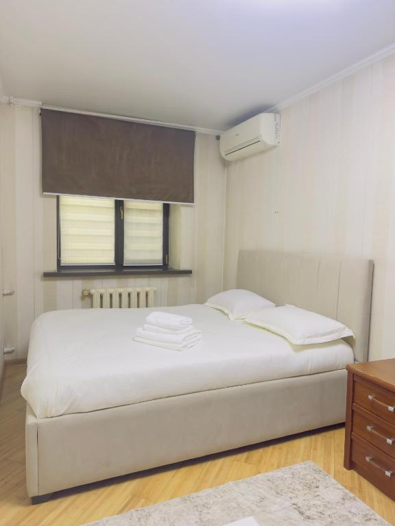 a bedroom with a large white bed and a window at Apartment in Almaty