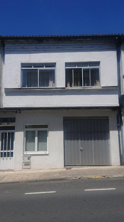 a white building with two garage doors on a street at Rooms Melide in Melide
