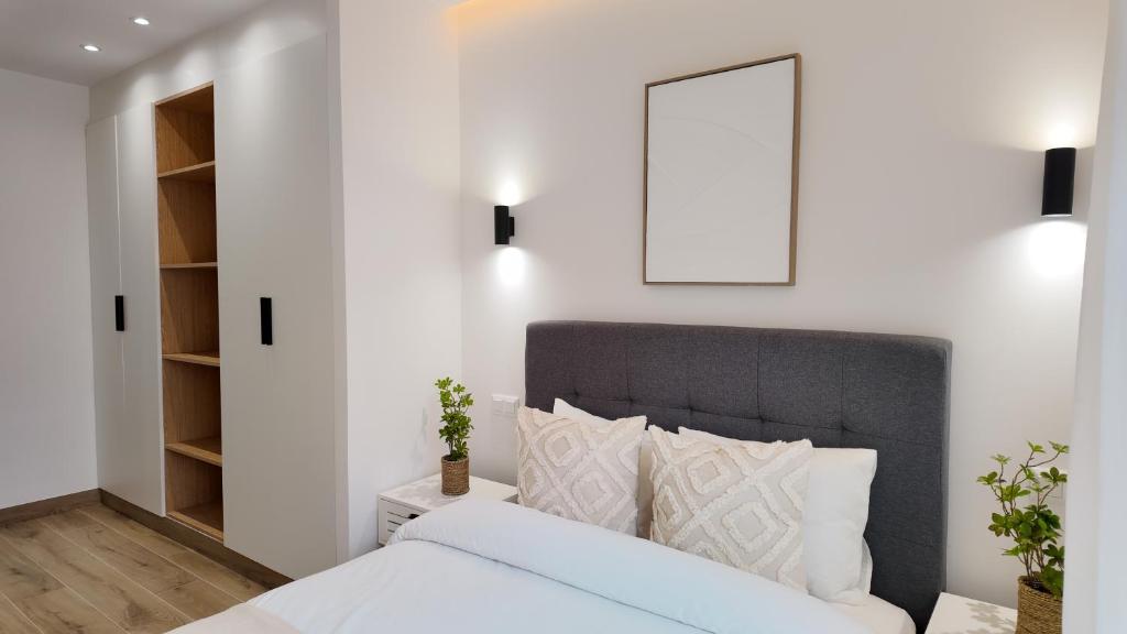 a bedroom with white walls and a bed with a gray headboard at The Eight Element Suites & Lofts in Madrid